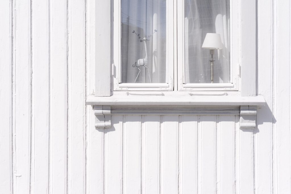 Del av en vit trähusfasad med fönster. Färgpigment: Blyvitt.