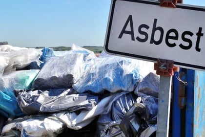 Deponi med inplastat asbestmaterial och en skylt med texten Asbest.